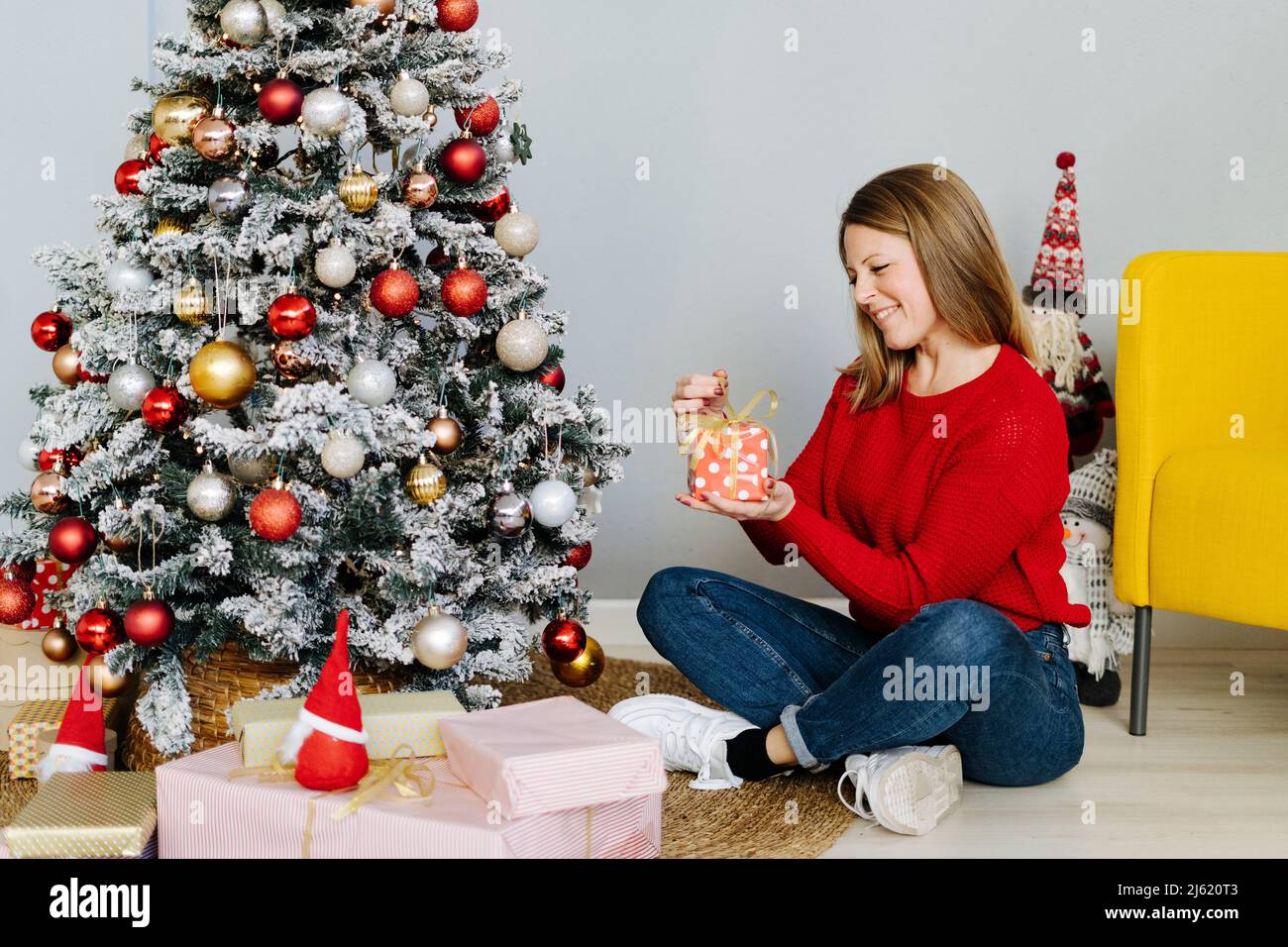 Happy woman opening Christmas presents sitting at home Stock Photo