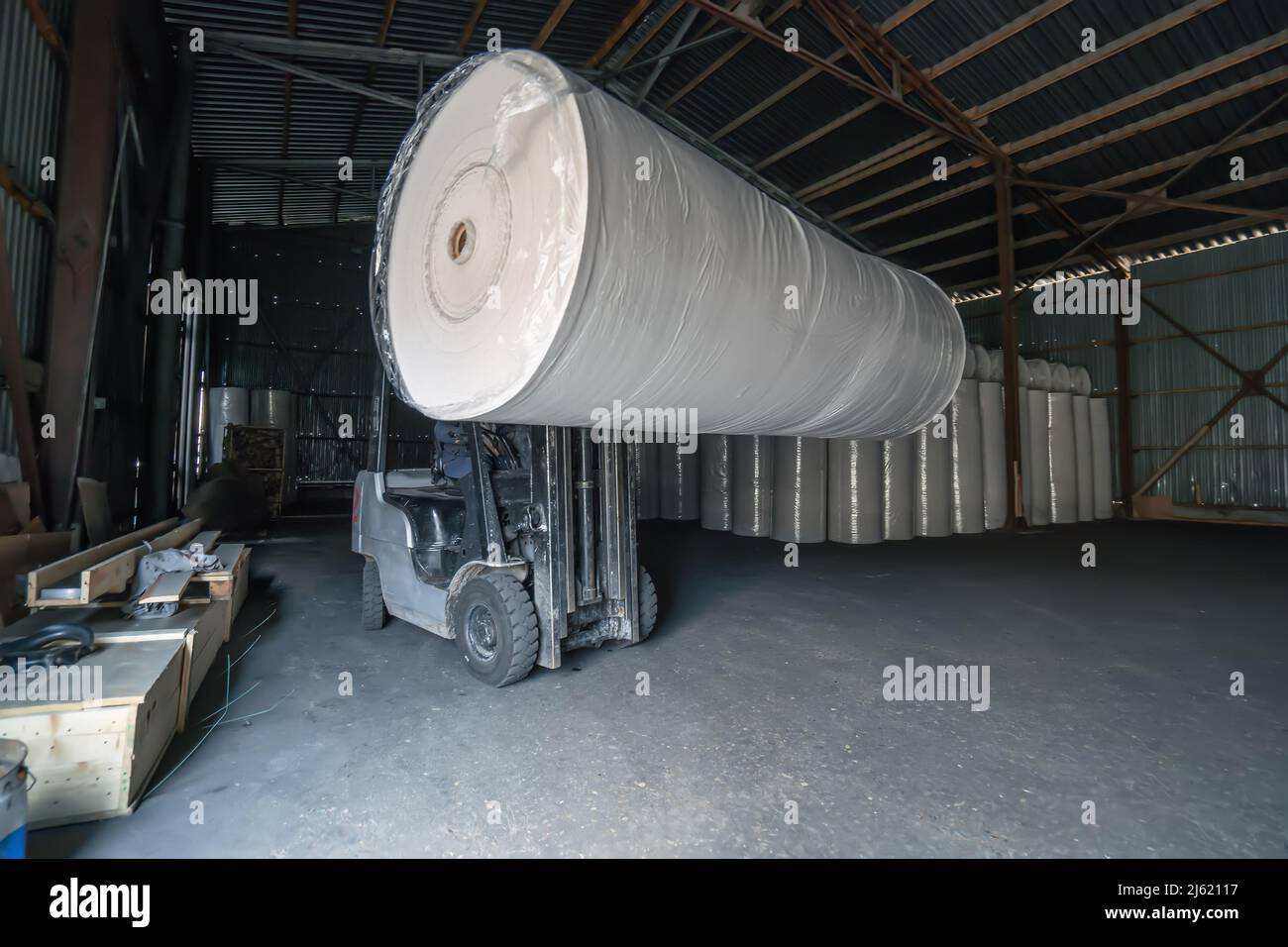 Forklift transports large roll of paper at recycling and toilet paper