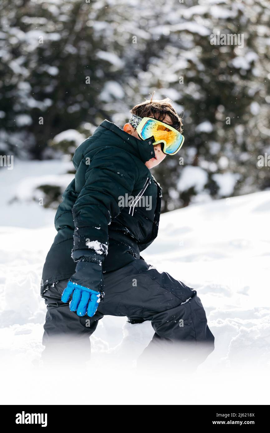 Boy wearing ski goggles walking in snow Stock Photo - Alamy
