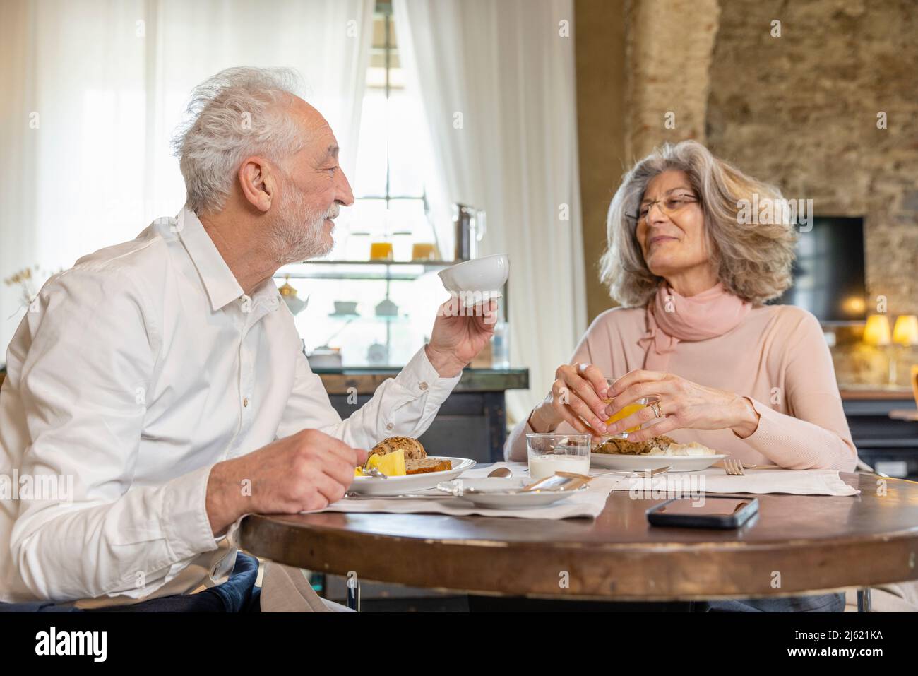 Senior couple having breakfast at table in boutique hotel Stock Photo