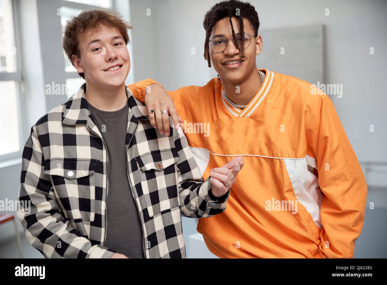 Smiling young man gesturing standing by friend Stock Photo