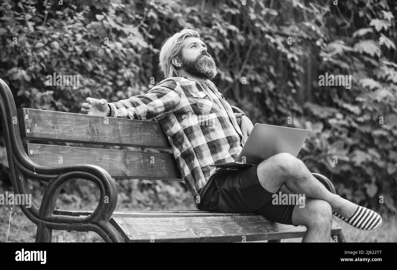 Hipster inspired work in park. Modern laptop. Remote job. Fresh air. Mobile internet. Online shopping. Agile business. Bearded guy sit bench park Stock Photo