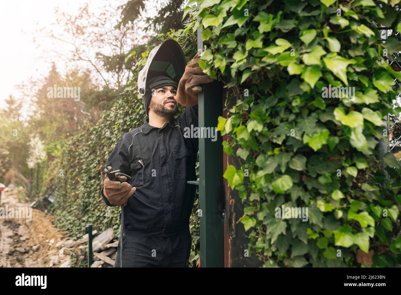 Welder with work tool working on metal gate at construction site Stock Photo