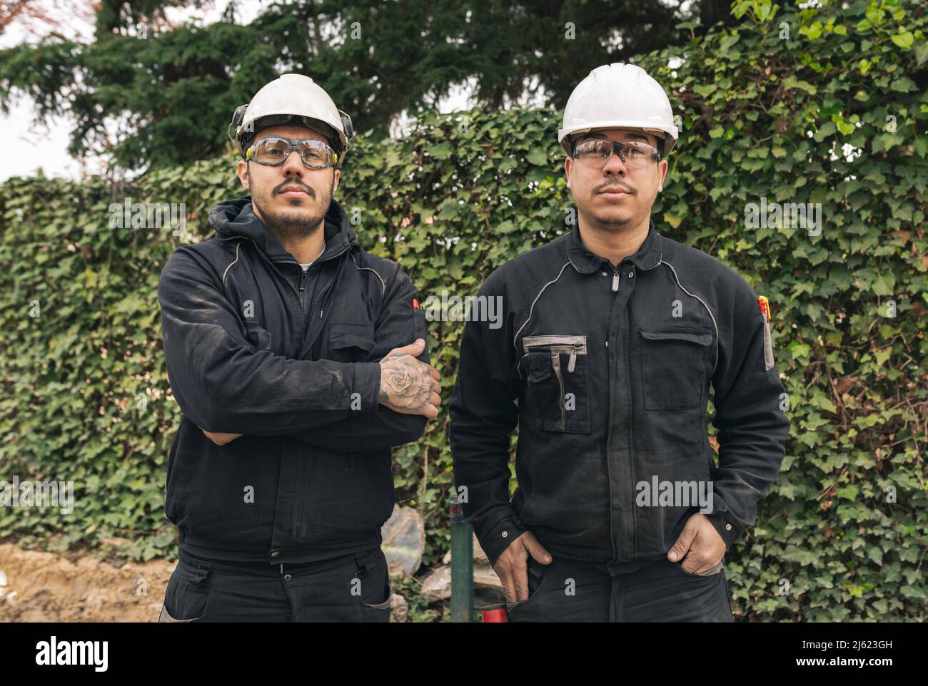 Construction workers wearing hardhats standing at construction site Stock Photo