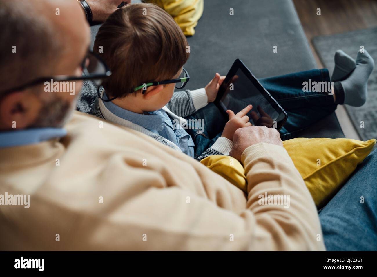 Boy e-learning through tablet PC by grandfather at home Stock Photo