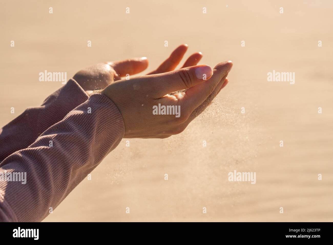 Young woman with sand in hand on sunny day Stock Photo