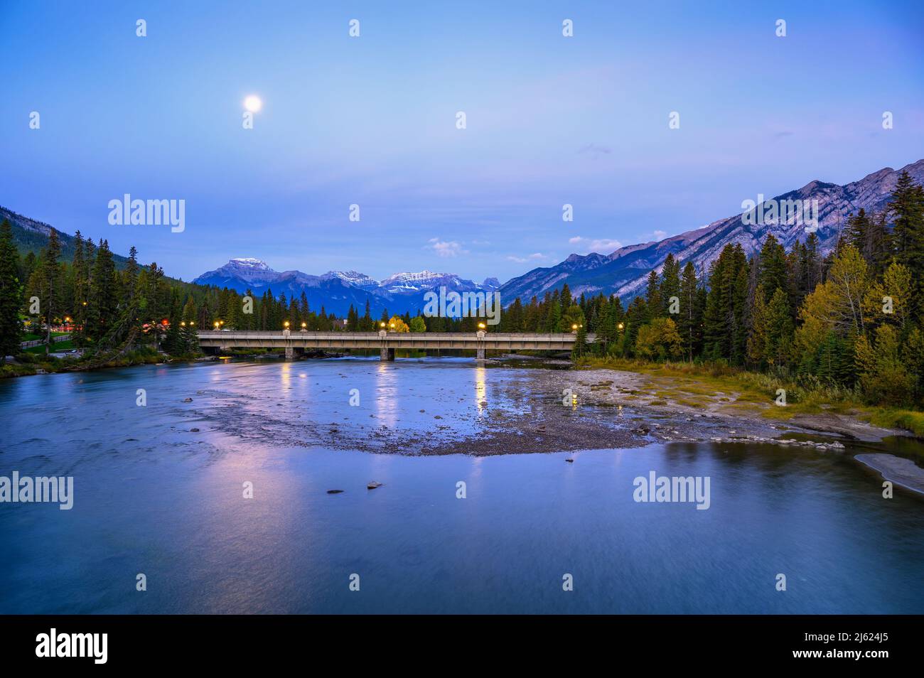 Moon over Banff Avenue Bridge and Bow River in Rocky Mountains, Canada Stock Photo