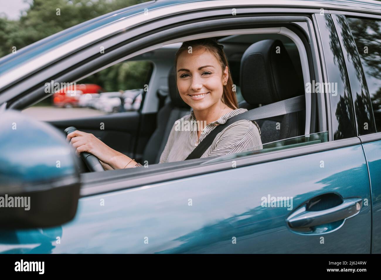 Smiling young woman looking through car window Stock Photo