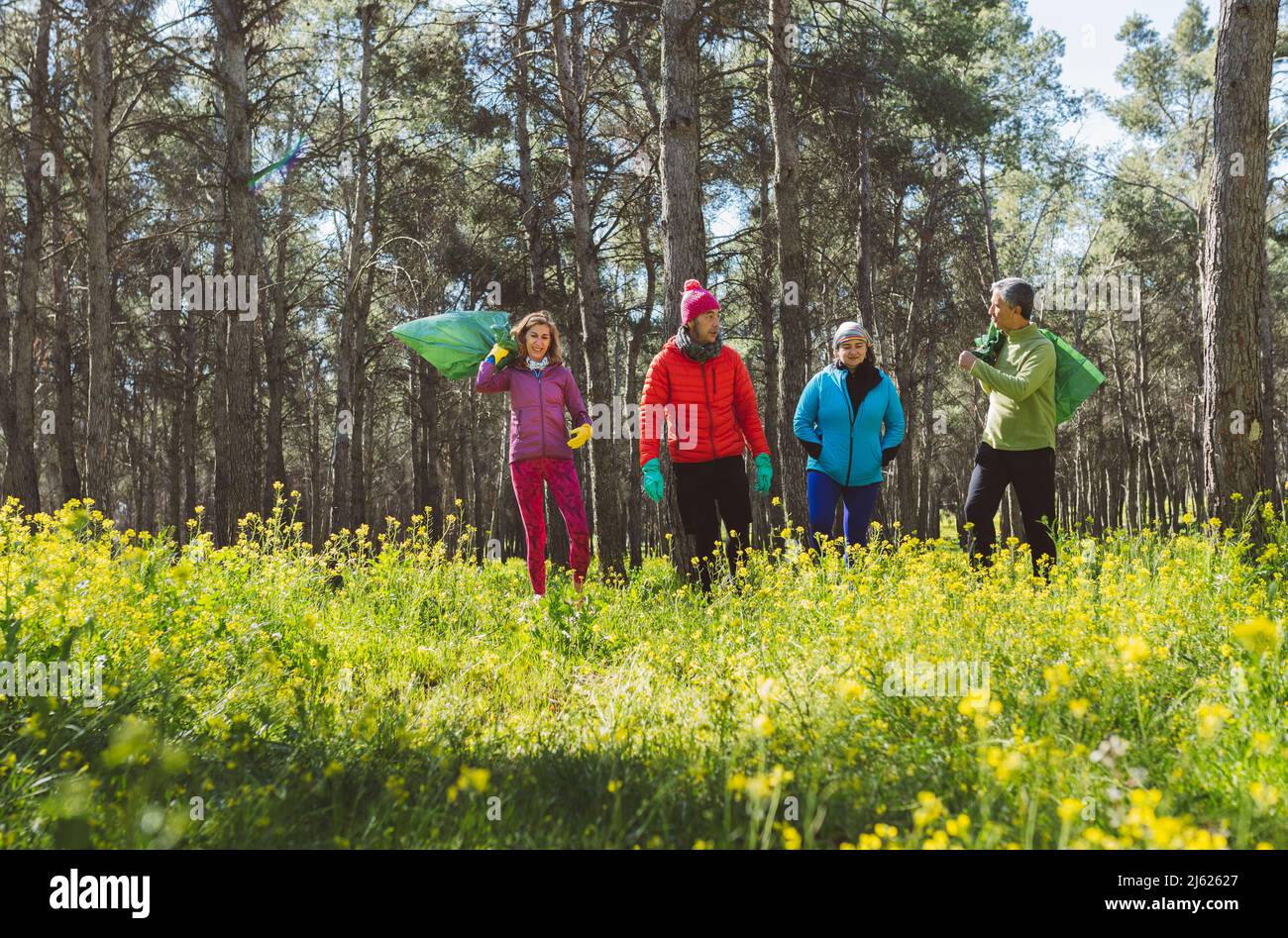 Volunteers with garbage bags walking in forest on sunny day Stock Photo