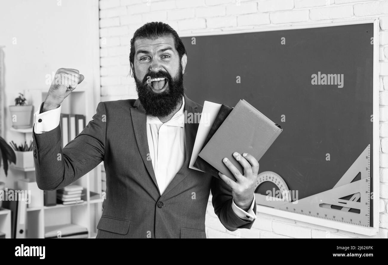great day. learning the subject. happy man with beard holding book. literature for studying. informal education. male student in school classroom Stock Photo