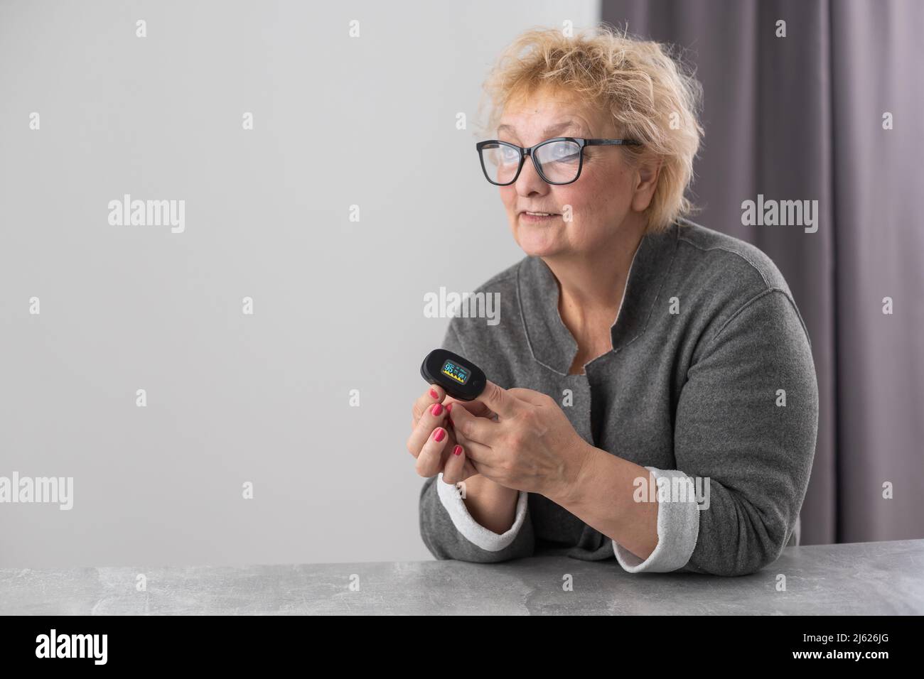Hand of senior woman with an attached pulse oximeter on fingertip,old ...