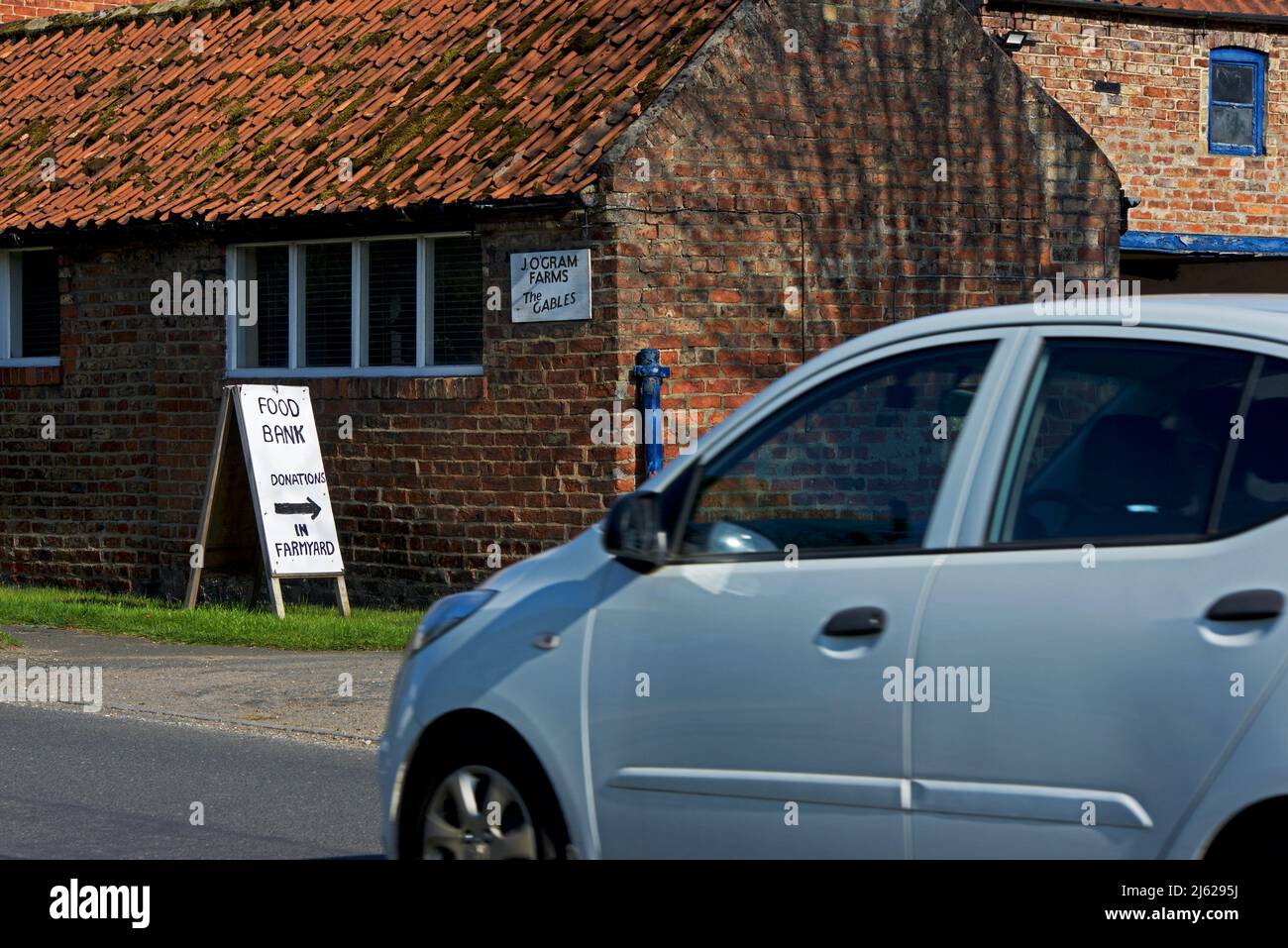 Car passing sign for food bank at farm, in the village of Allerton, East Yorkshire, England UK Stock Photo