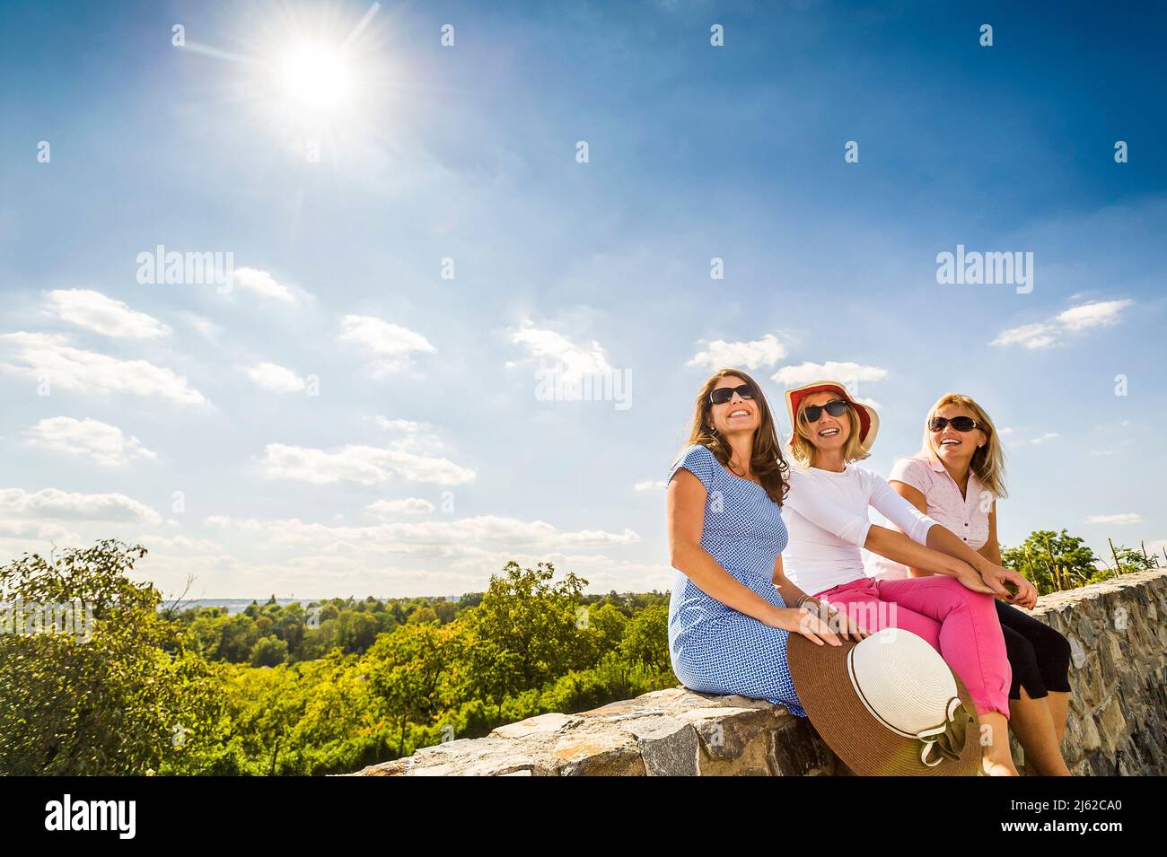 three women sitting on the stone wall enjoying coutryside Stock Photo