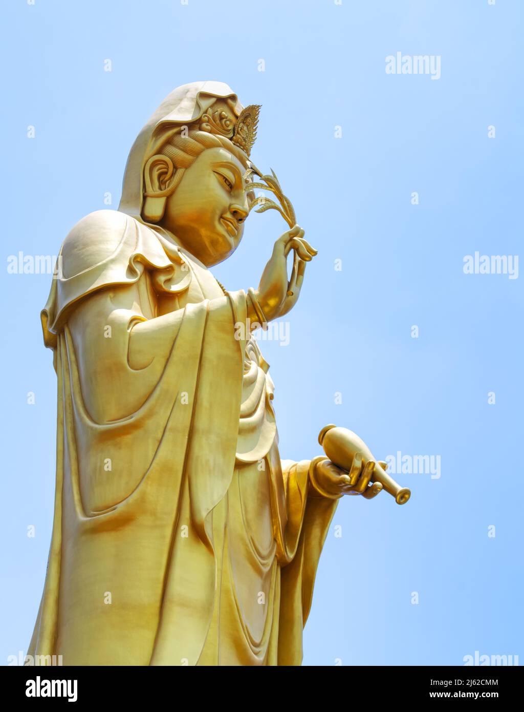 The big golden statue of Guan Yin, summer blue sky with strong sunlight