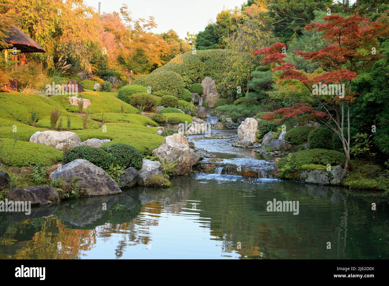 A new pond garden or yoko-en of Taizo-in temple with a stream that cascades around rocks and azaleas and empties into a pool. Kyoto. Japan Stock Photo