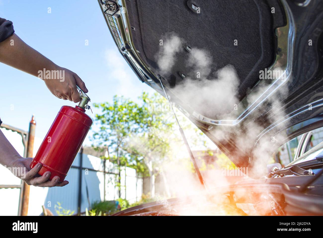 The driver of the car directs a powder fire extinguisher at the engine