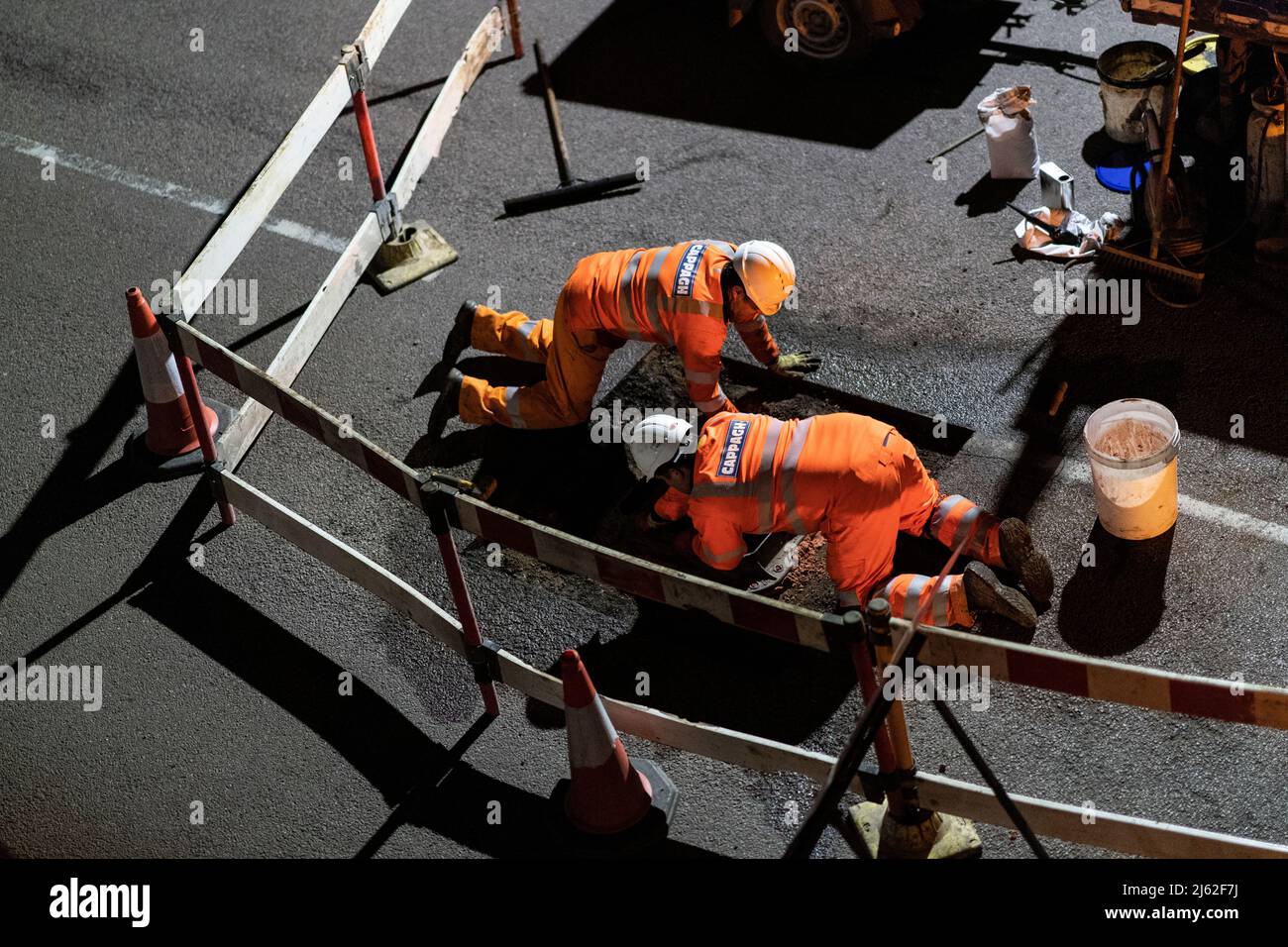 Night time roadworks, repairing a broken manhole cover in the road, in Hertfordshire, UK. Work carried out by contractors Cappagh, on behalf of Thames Water. Photo: David Levenson/Alamy Stock Photo