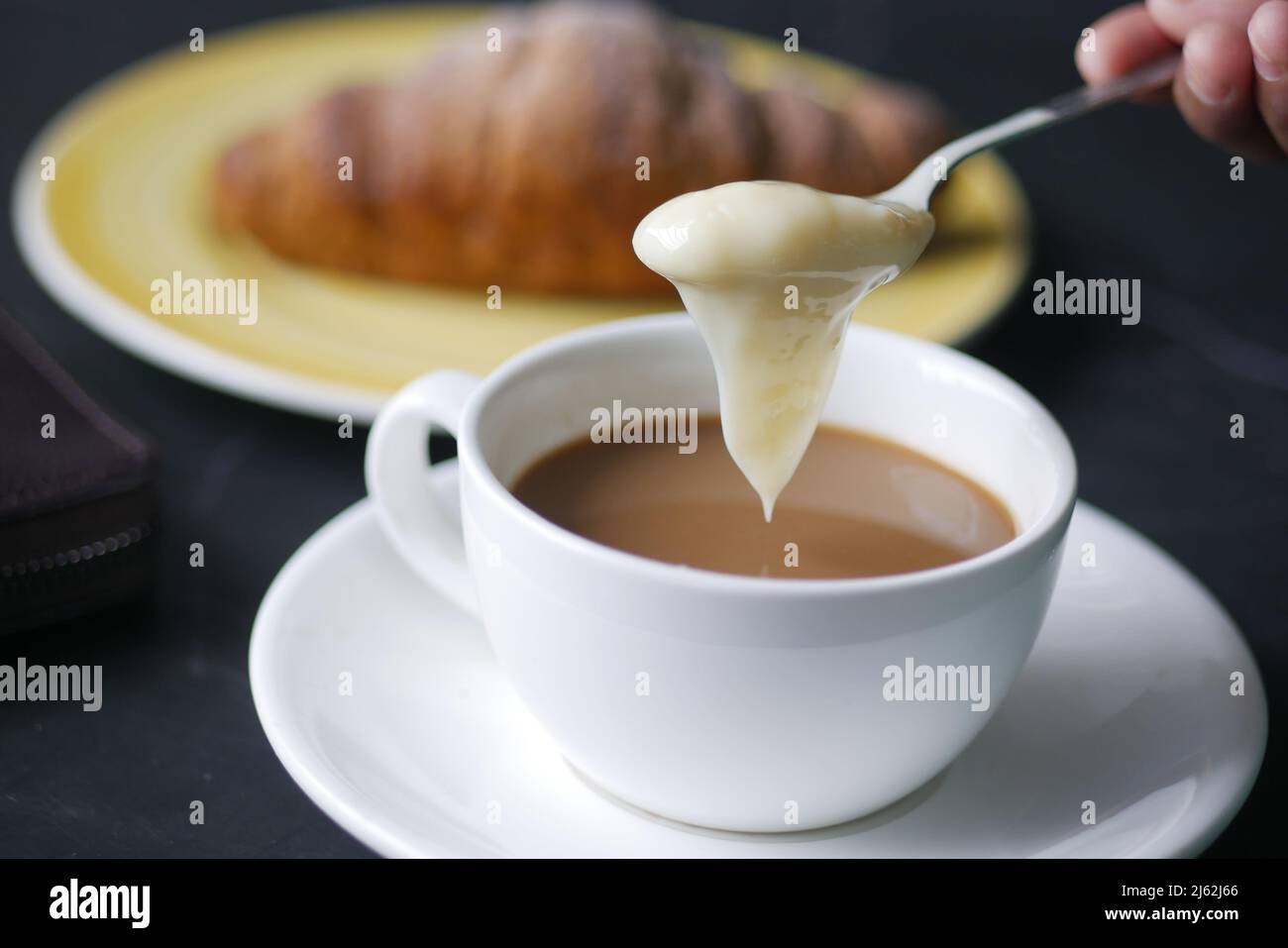 pouring condensed milk in cup of tea Stock Photo Alamy