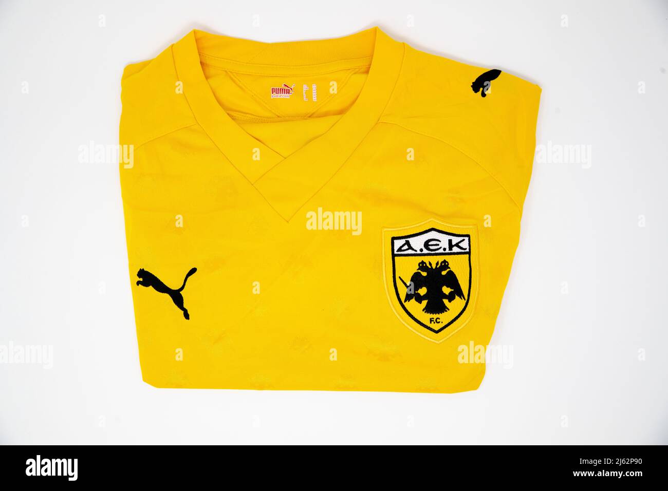 AEK Athens FC badge on the front of a folded yellow puma football shirt Stock Photo