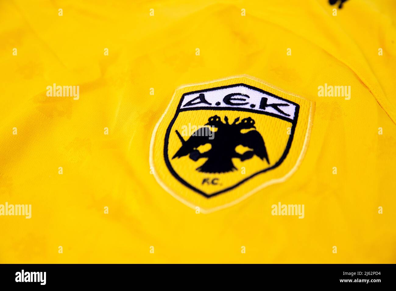 AEK Athens FC badge on the front of a folded yellow puma football shirt Stock Photo
