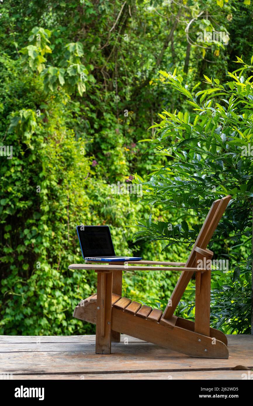 A laptop on a Adirondack chair in a rainforest lodge, digital nomad concept, Chiriqui province, Panama, Central America Stock Photo