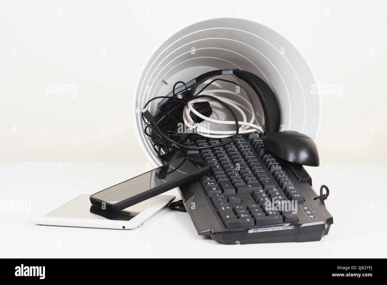 Recycling bin and old digital tablet, cell phone, headphone, cords and