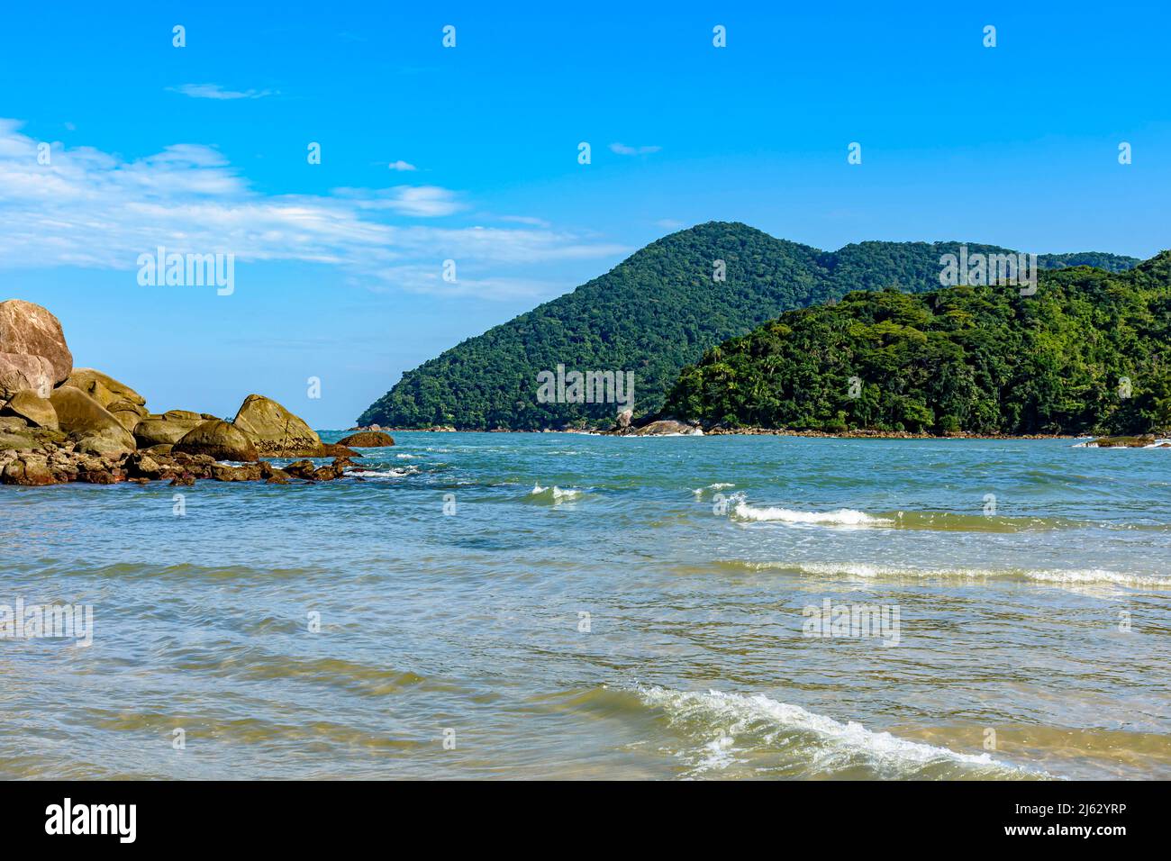 The sea with calm and transparent waters between the rocks, mountains and tropical forests of Bertioga on the coast of Sao Paulo, Brazil Stock Photo