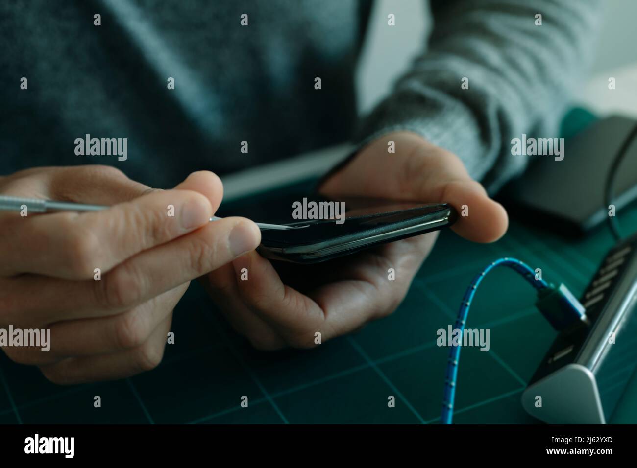 closeup of a young caucasian man removing the broken screen protector of a smartphone, sitting at a table Stock Photo