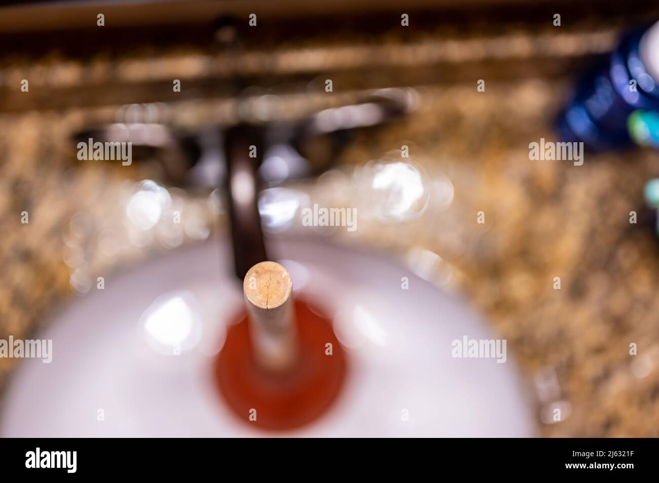 Using a plunger on a bathroom sink plugged with Hair and scum in a pool