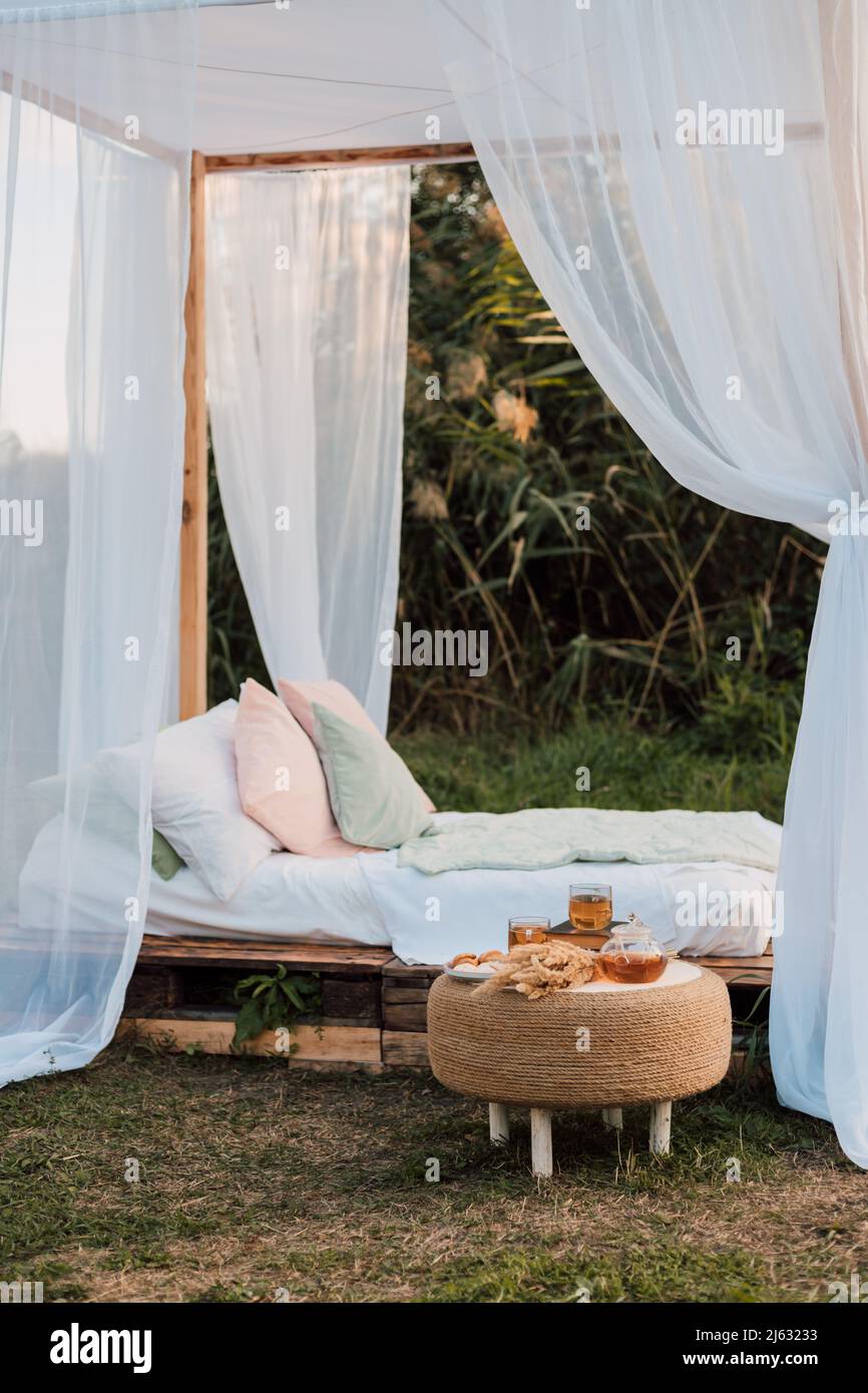 Beautiful wooden bed with white bed and canopy in nature in the village