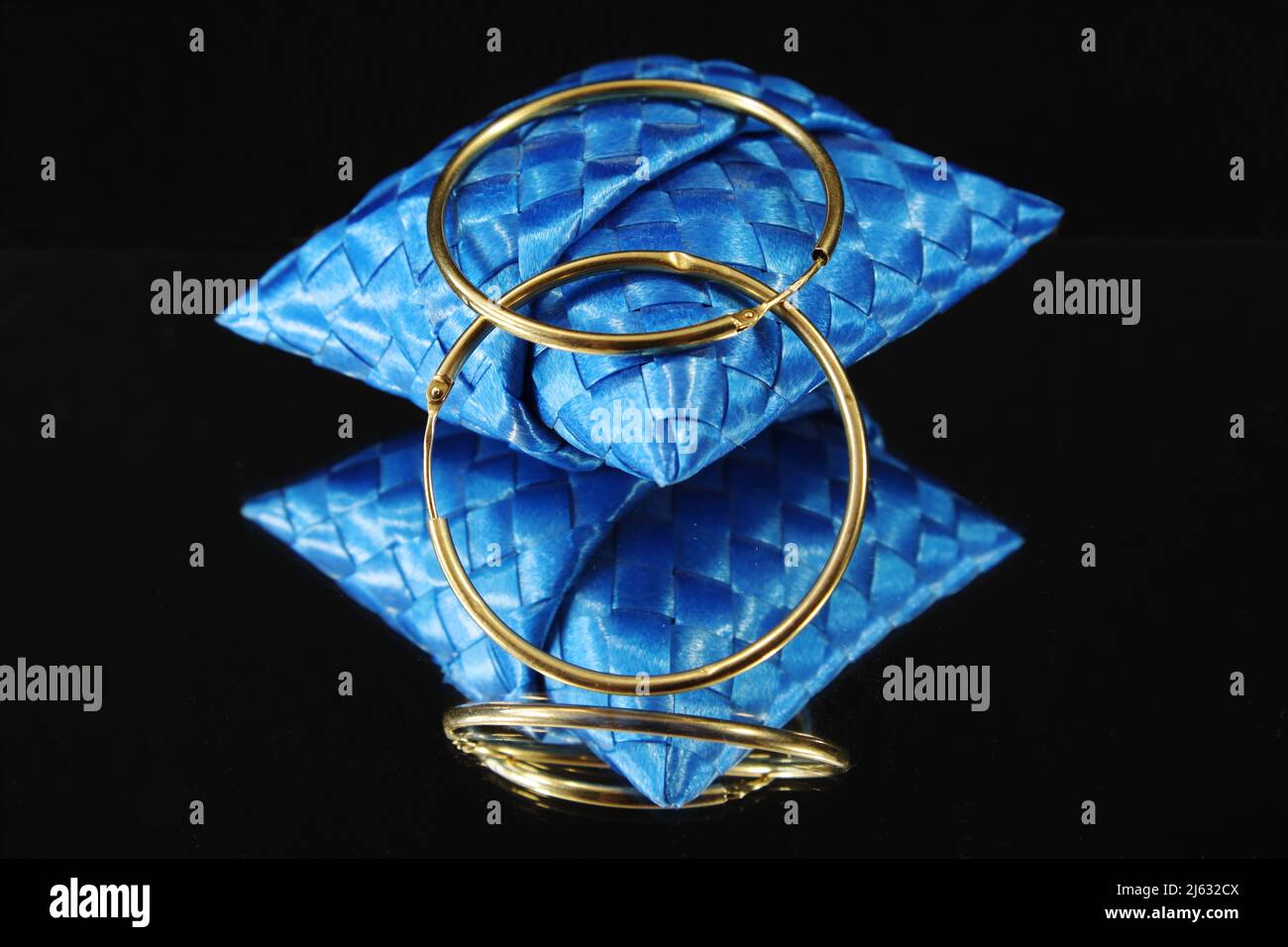 Gold mirror-effect earrings on a black background Stock Photo