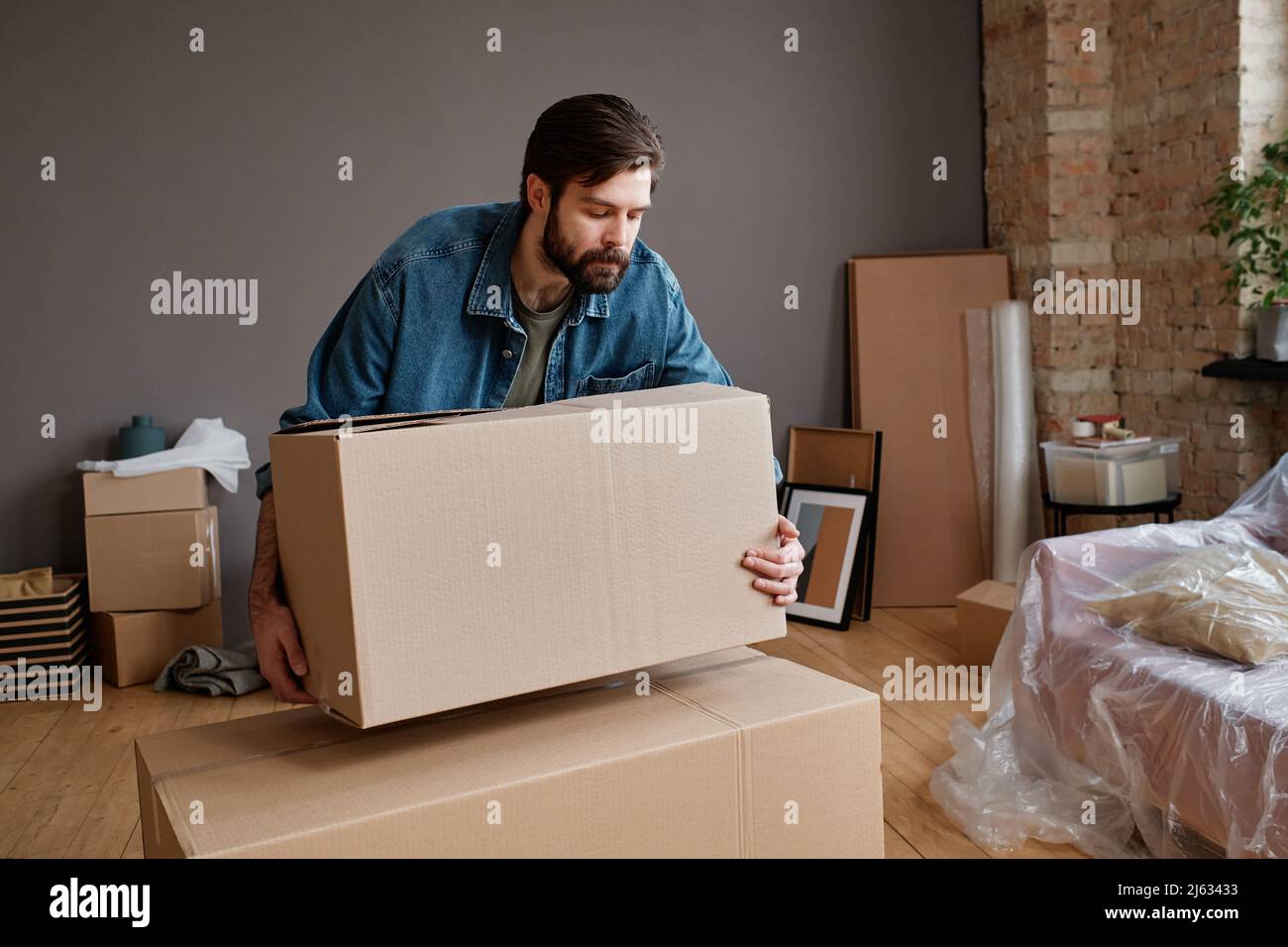 Horizontal shot of young man moving to new apartment bringing and