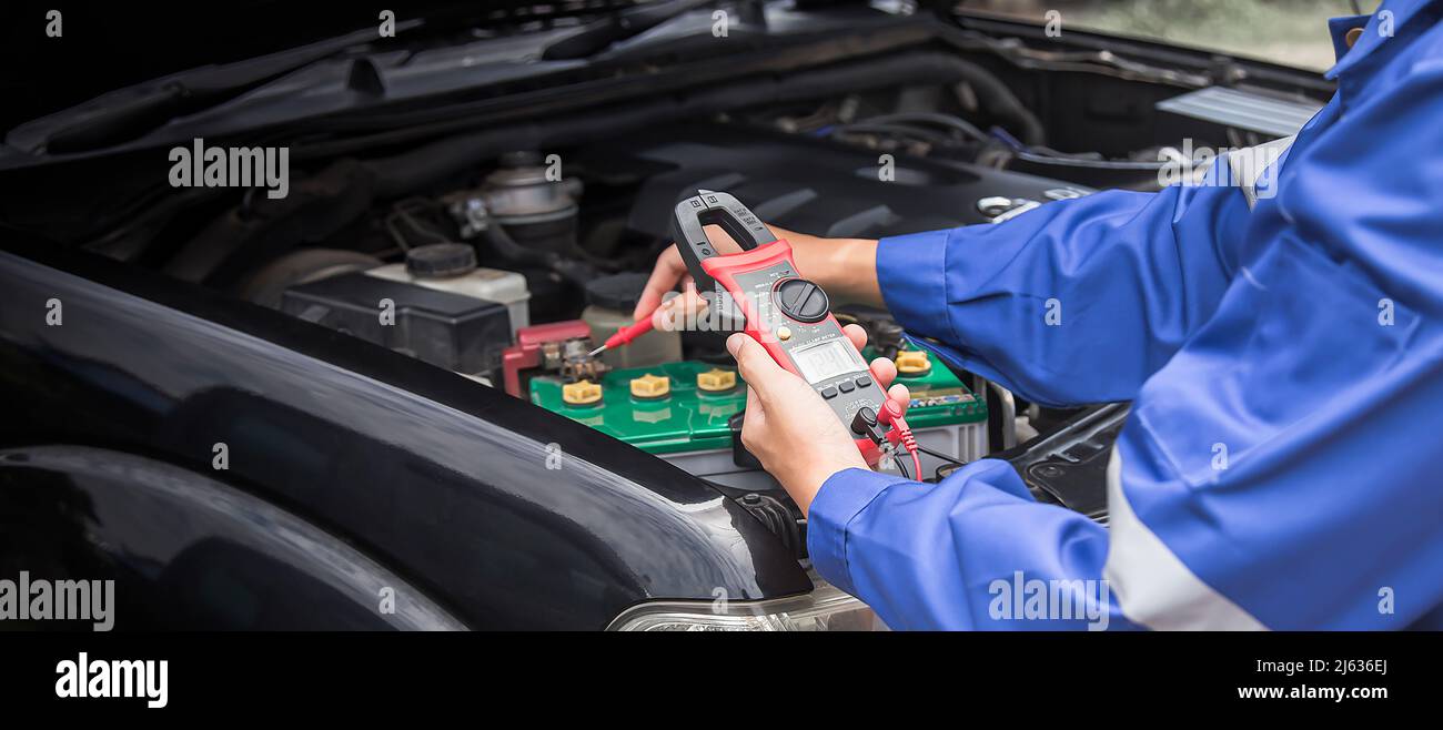 A technician is checking the car battery for availability Stock Photo