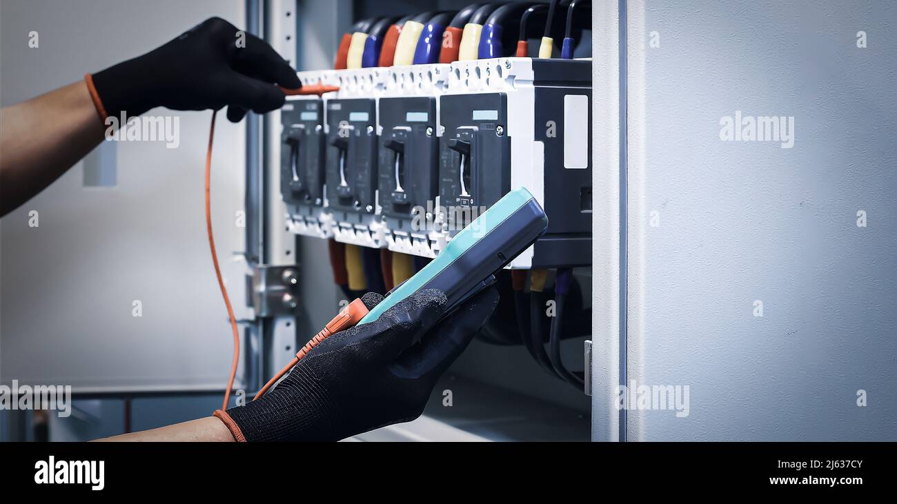 Electrical engineers check electrical control devices with a multimeter