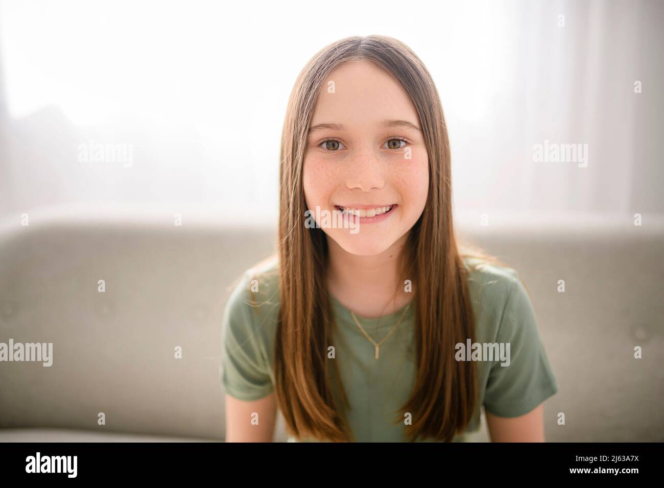 Smiling young girl sit on sofa looking at camera Stock Photo - Alamy