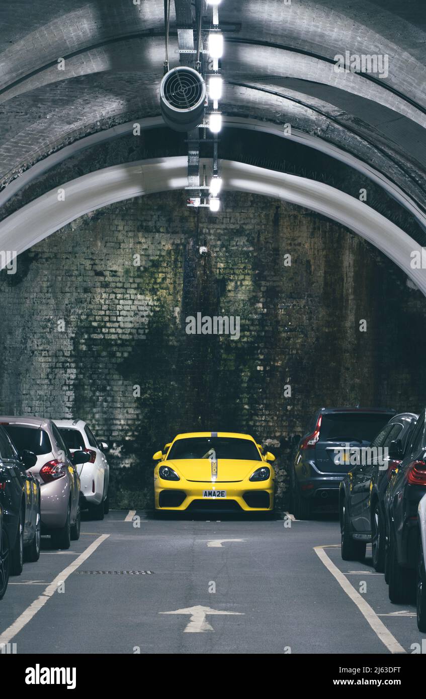 An underground car park or parking lot in a city making good use of limited space with a bright yellow car prominent Stock Photo