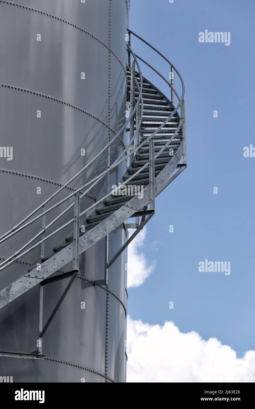 Abstract image of lthe stairs leading to the top of a riveted steel storage silo at a food processing facility. Stock Photo