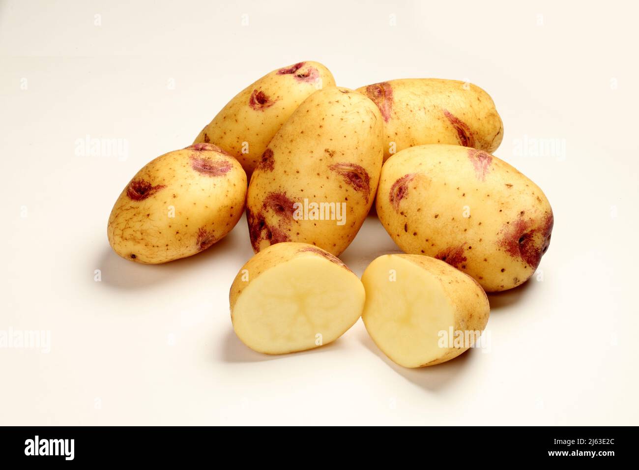 A pile of Yukon Royal potatoes on a white background.  These potatoes feature the 'Purple Kiss' mark around each eve, that distinguishes theis speceal Stock Photo