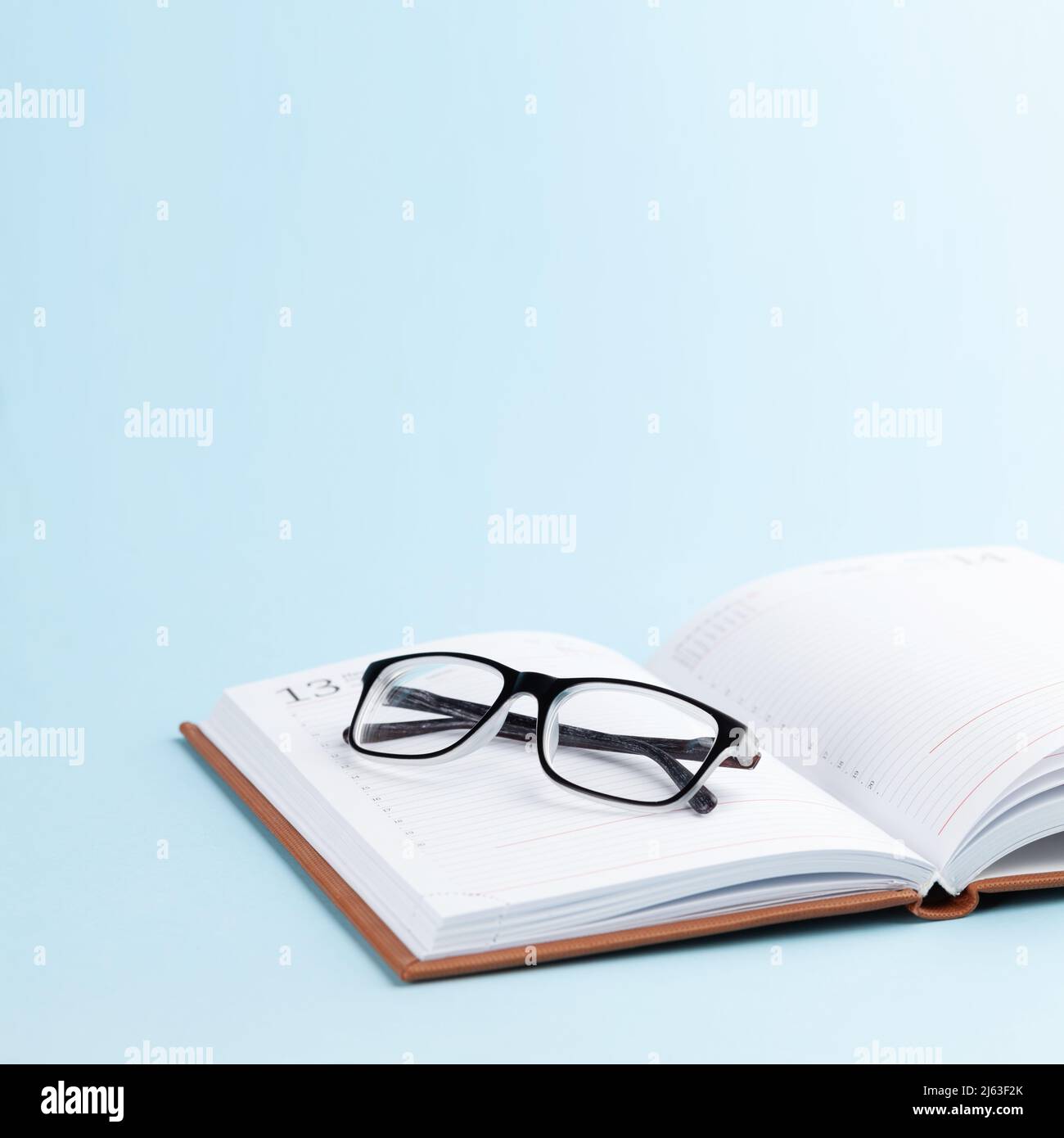 Notepad and glasses over blue background with copy space Stock Photo