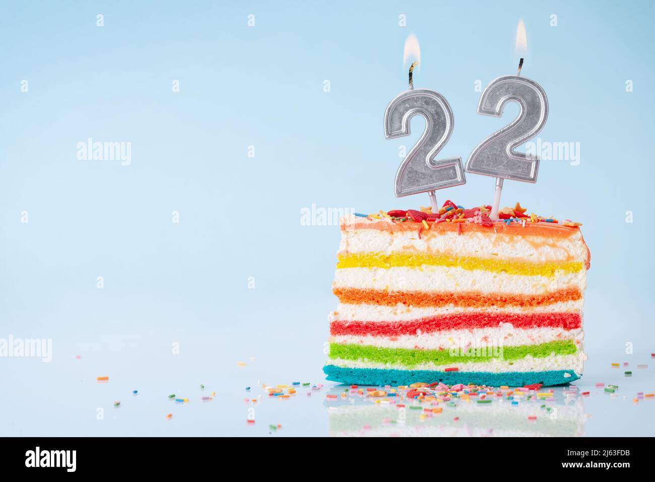Birthday cake with burning number 22 candles on blue background with