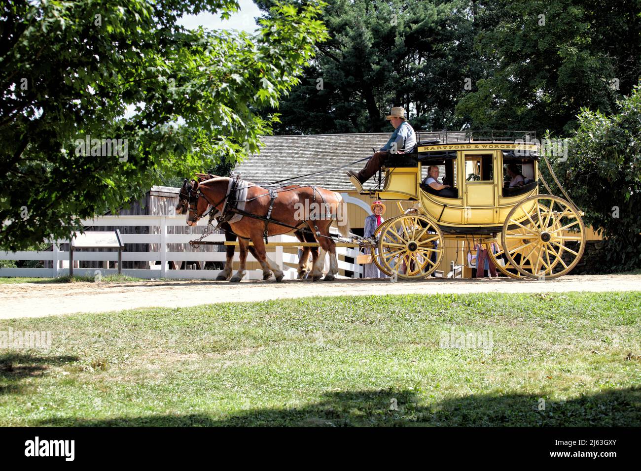 Visitors ride in a horsedrawn stagecoach, at  Old Sturbridge Village in Sturbridge Massachussetts. Stock Photo