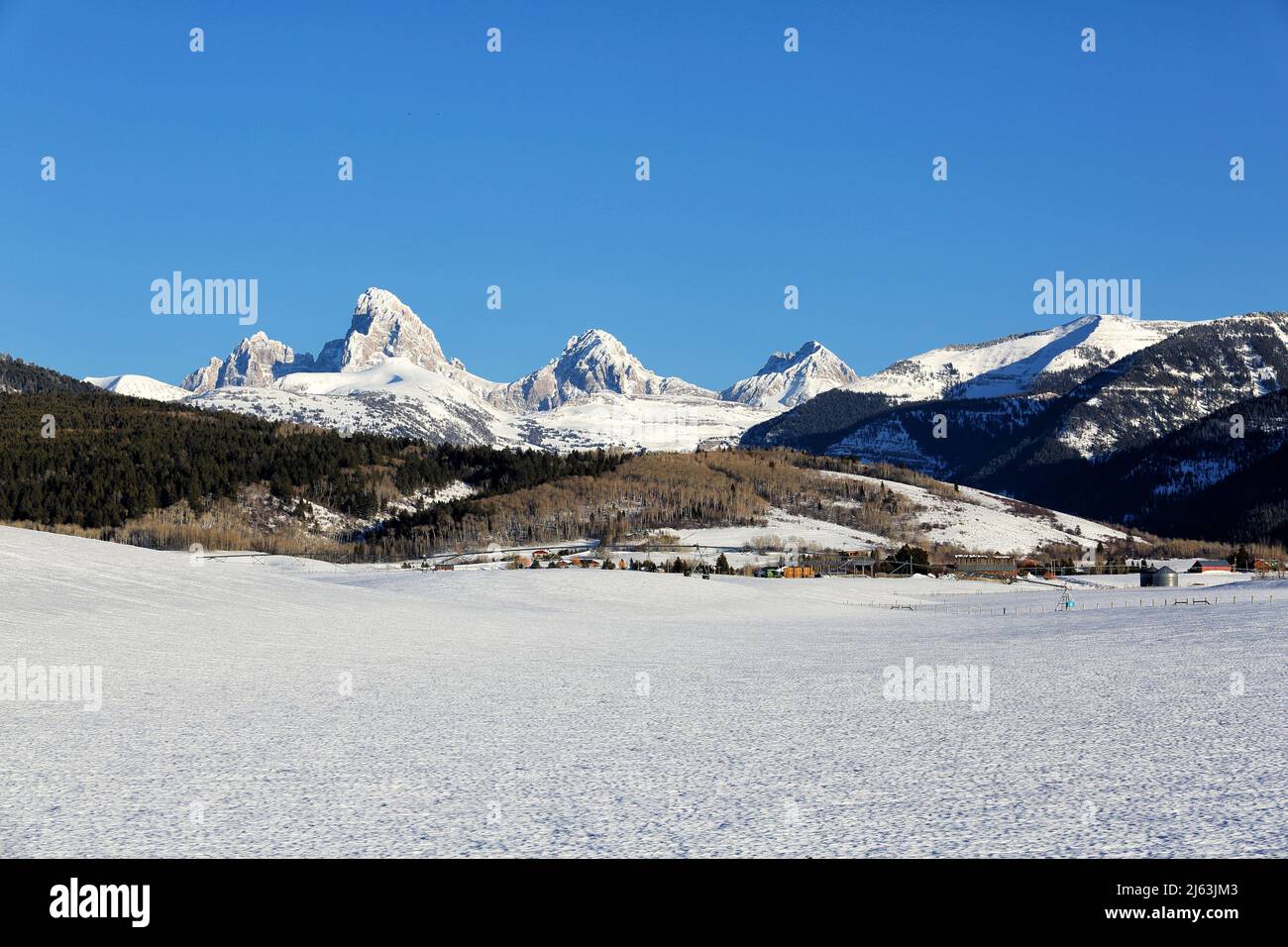 The snow covered Grand Teton mountain range during a harsh Idaho Winter, holds the snow-pack that will provide water throughout the year.. Stock Photo