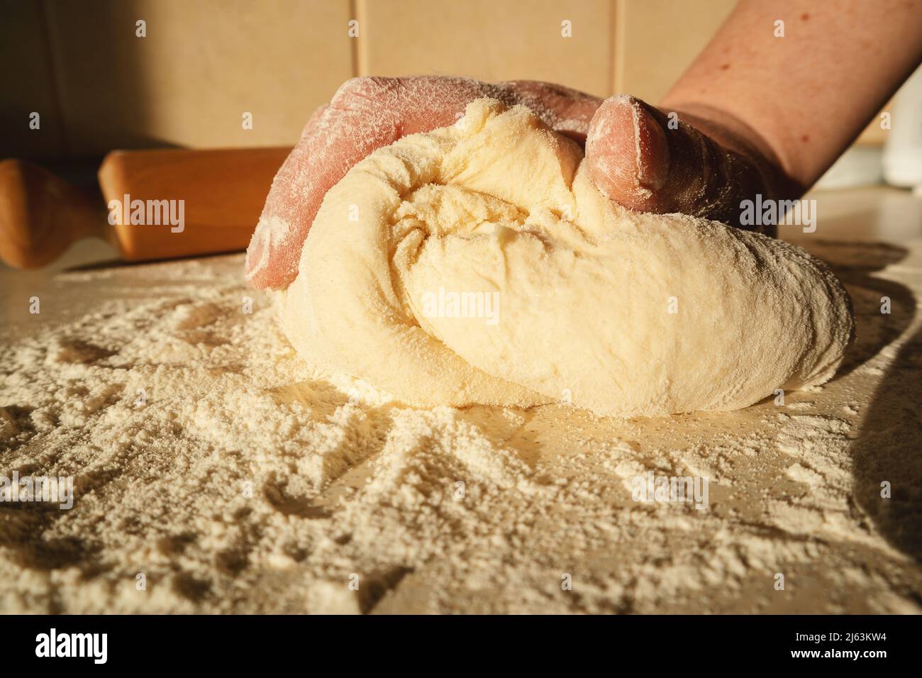 Preparing the dough for bread, kneading the dough with hands on the table. Stock Photo