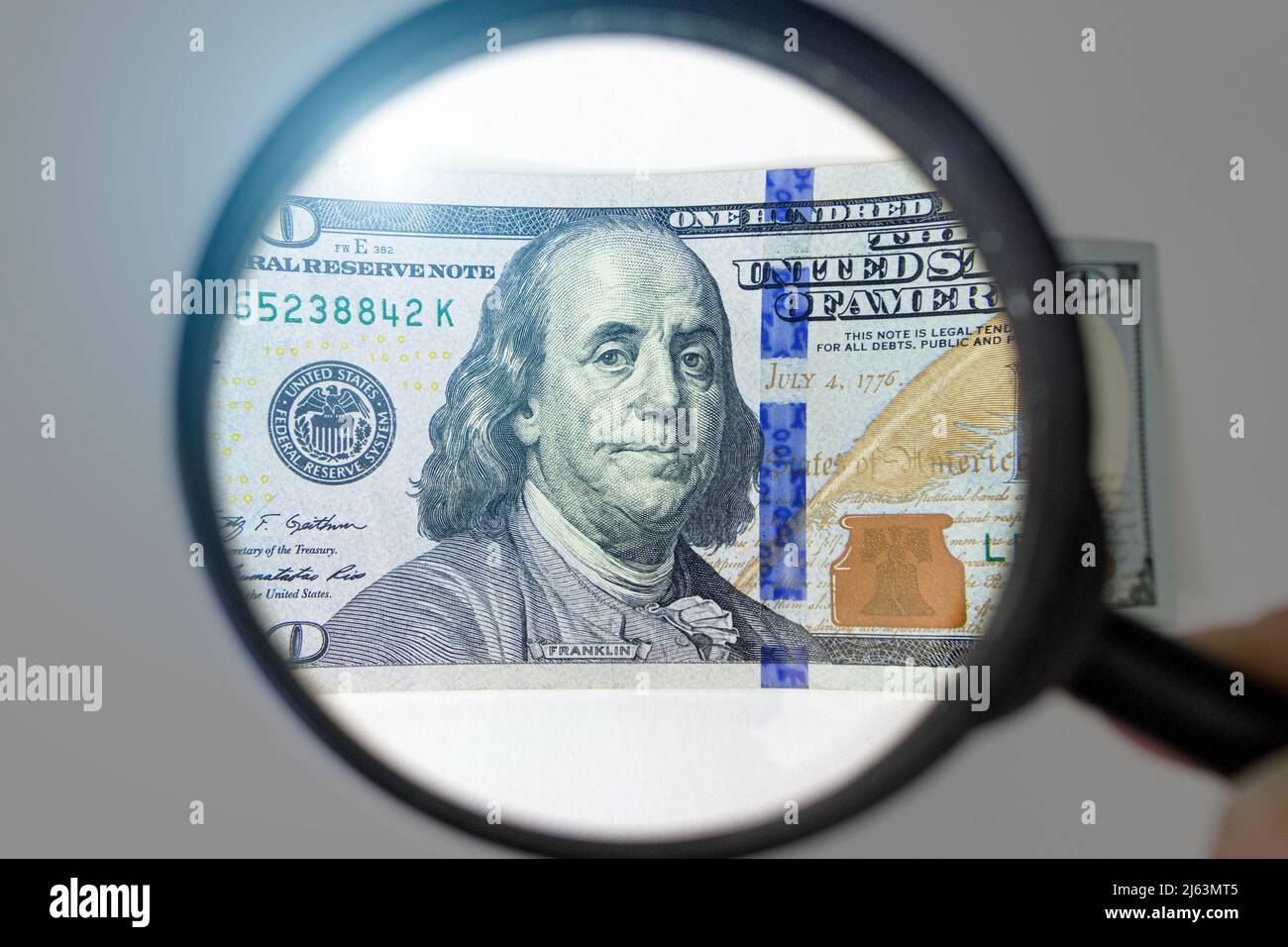 Magnifying Glass - 100 US Dollars. Concept on the theme of checking money for authenticity Stock Photo