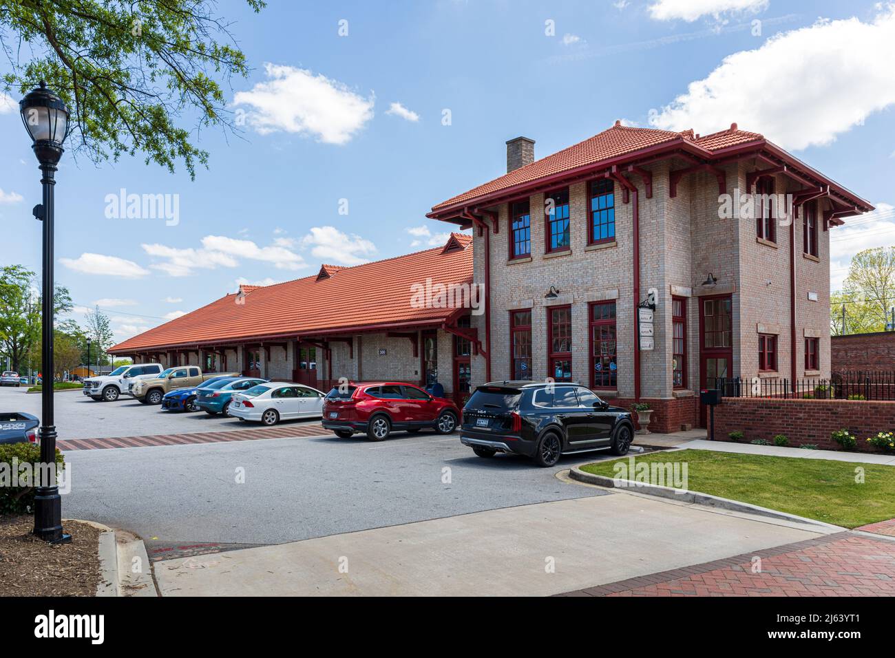 GREER, SC, USA 24 APRIL 2022: Old Train Depot, now housing offices and small businesses.  Diagonal view of building and parking lot. Stock Photo