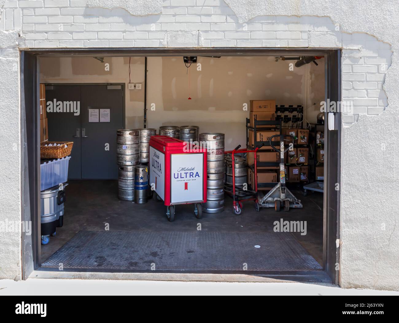 GREER, SC, USA 24 APRIL 2022: View thru bay door of storage room showing beer kegs and a rolling cart advertising Michelob Ultra beer. Stock Photo