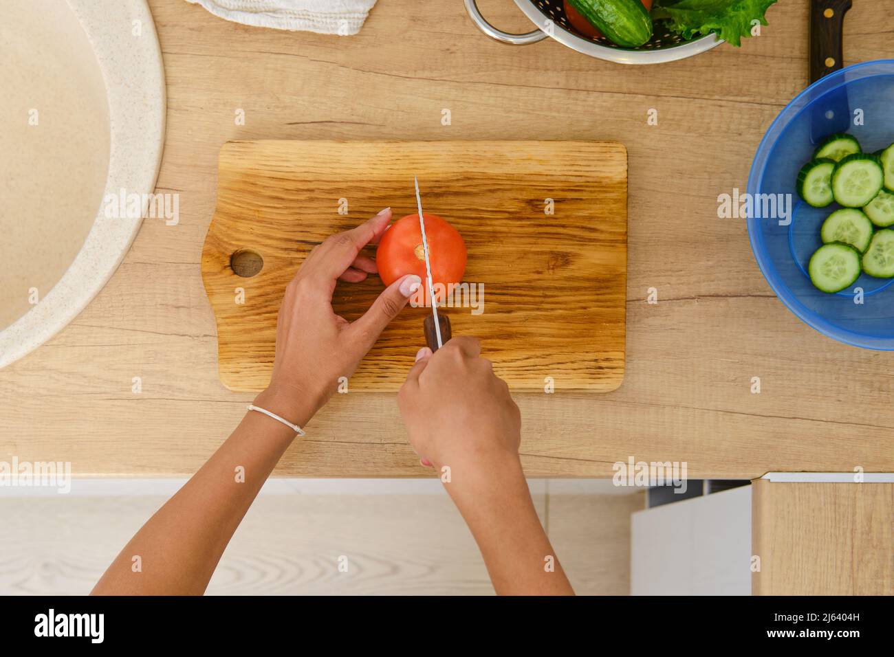 Top view at the hands of african american woman cutting tomato for