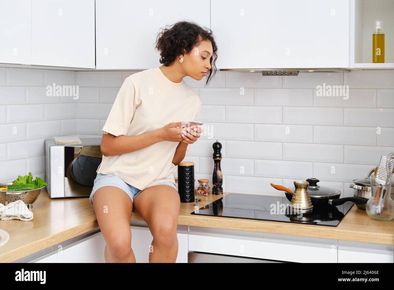 African woman looks into a cezve with coffee on the stove Stock Photo