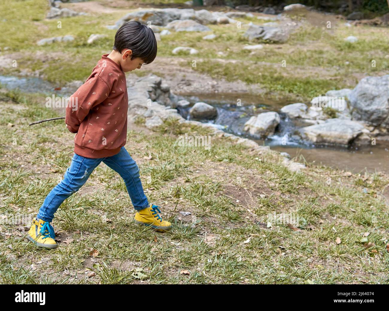 latino boy playing by the side of a lake in casual dress on an autumn afternoon . horizontal Stock Photo