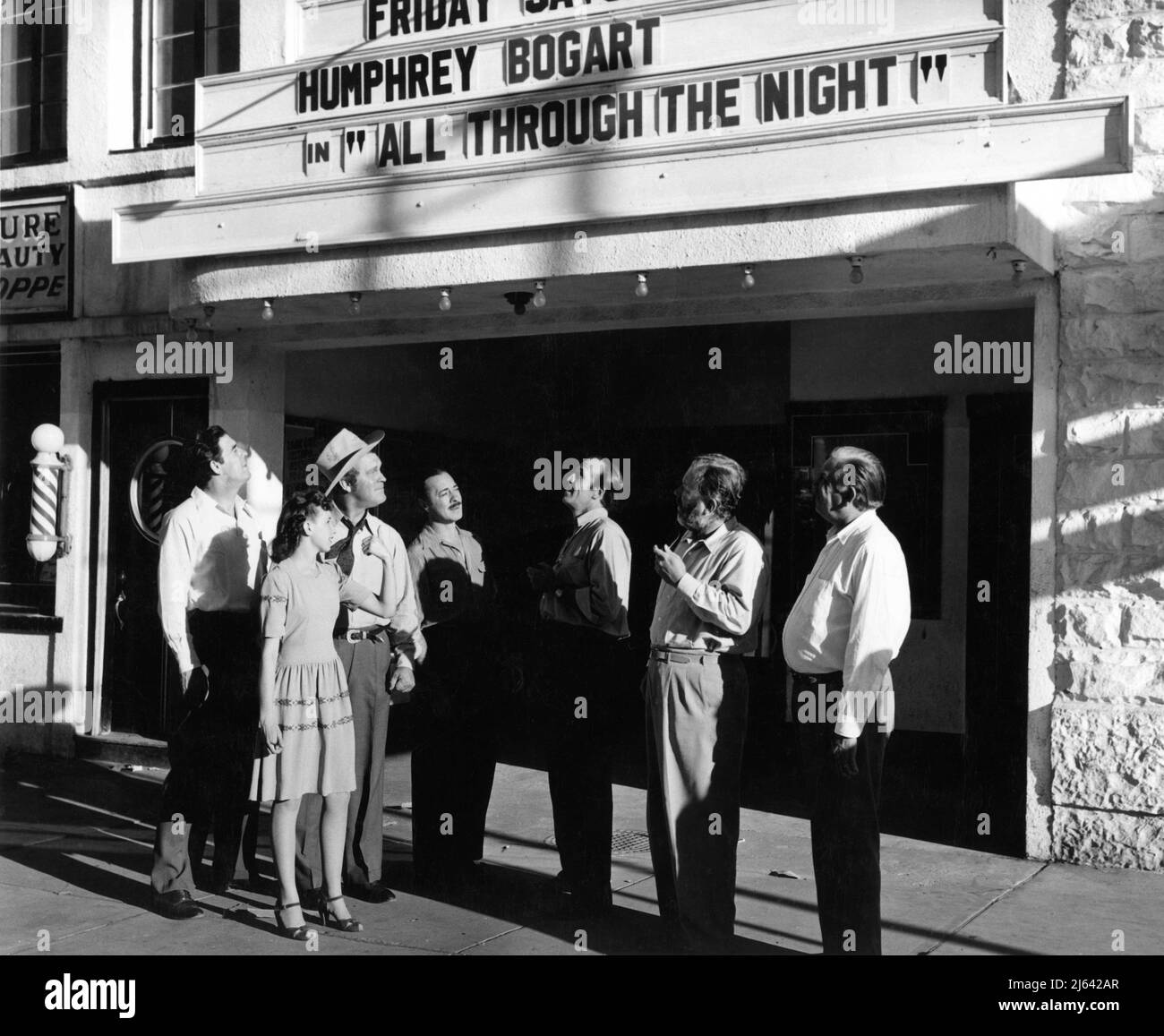 Local Girl from Kanab. Utah stands outside local movie theatre showing Humphrey Bogart in All Through The Night with Cast Members GLENN STRANGE GUINN ''BIG BOY'' WILLIAMS BERNARD NEDELL ETHAN LAIDLAW EDGAR BUCHANAN and SLIM WHITAKER on location there in July 1942 filming THE DESPERADOES 1943 director CHARLES VIDOR original story Max Brand Columbia Pictures Stock Photo